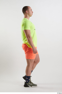 Joel  1 dressed green sneakers orange shorts side view…